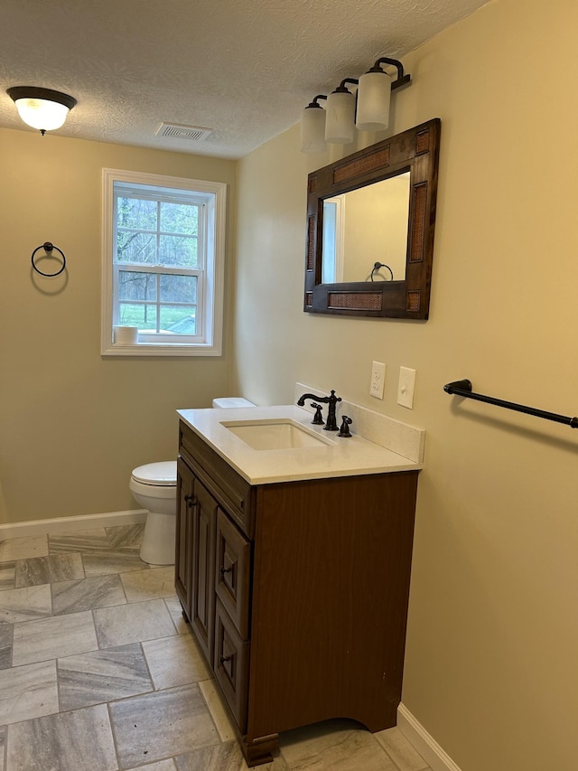 bathroom featuring a textured ceiling, visible vents, baseboards, vanity, and toilet