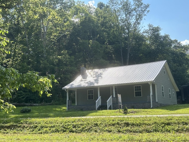 view of front of house with a porch, metal roof, a front yard, and a chimney