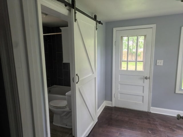 interior space featuring baseboards, dark wood-style floors, and a barn door
