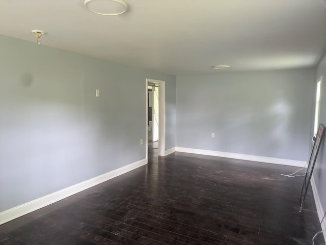 spare room with dark wood-style flooring and baseboards