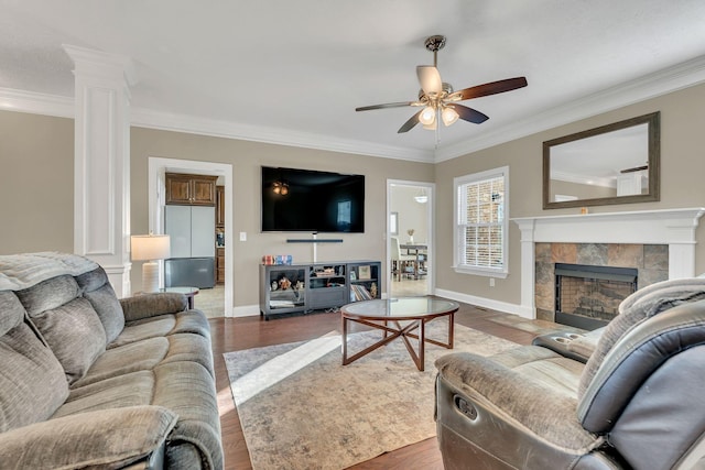 living area with ornamental molding, a ceiling fan, ornate columns, and wood finished floors