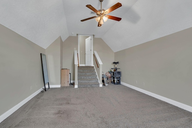 unfurnished living room featuring a ceiling fan, vaulted ceiling, baseboards, carpet floors, and stairs