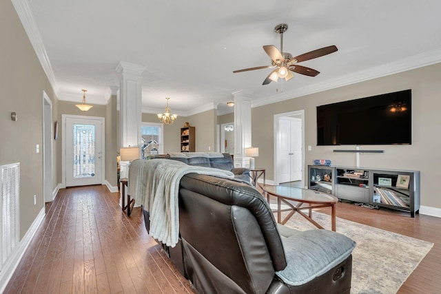 living area with ceiling fan with notable chandelier, baseboards, decorative columns, ornamental molding, and hardwood / wood-style flooring