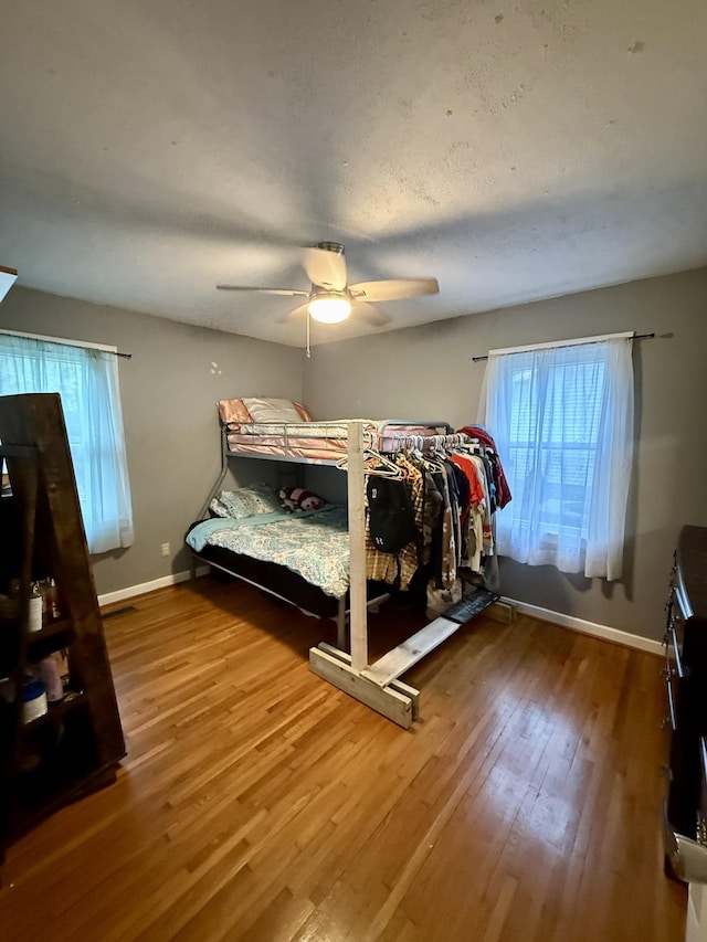 bedroom with a ceiling fan, baseboards, and wood finished floors