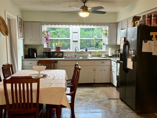 kitchen featuring light countertops, a ceiling fan, black fridge, and a sink