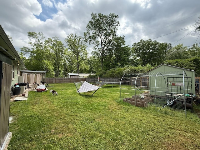 view of yard with a fenced backyard, an outbuilding, and a vegetable garden