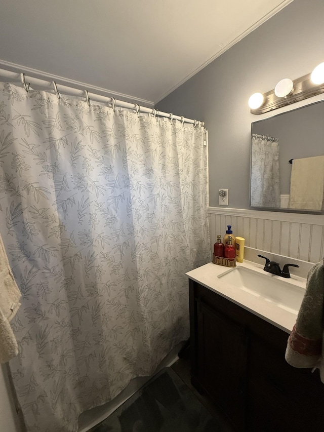 bathroom featuring vanity, ornamental molding, and wainscoting