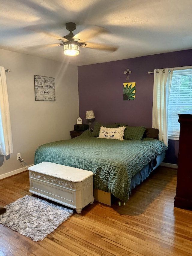 bedroom with a ceiling fan, baseboards, and wood finished floors