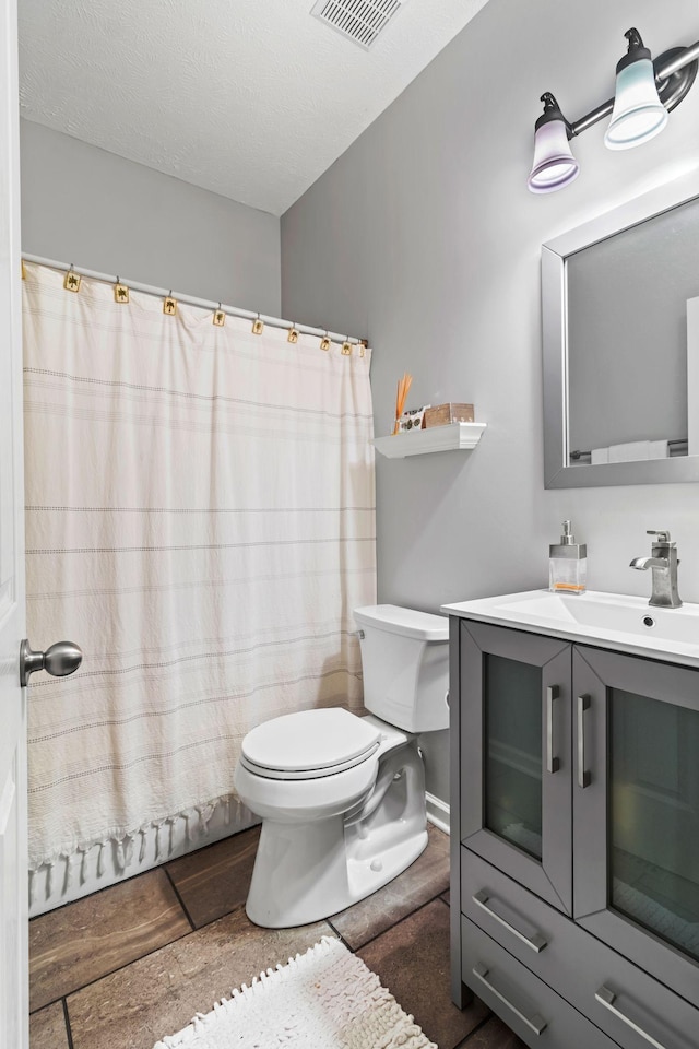 full bathroom featuring toilet, vanity, visible vents, and curtained shower