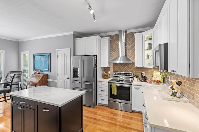kitchen with a kitchen island, appliances with stainless steel finishes, tasteful backsplash, white cabinetry, and wall chimney exhaust hood