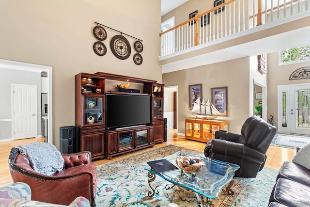 living room featuring light wood-type flooring, baseboards, and a towering ceiling