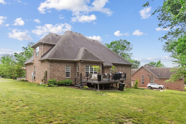 back of house featuring a lawn, a deck, and brick siding