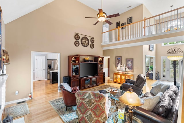 living area featuring visible vents, ceiling fan, high vaulted ceiling, light wood finished floors, and a wealth of natural light