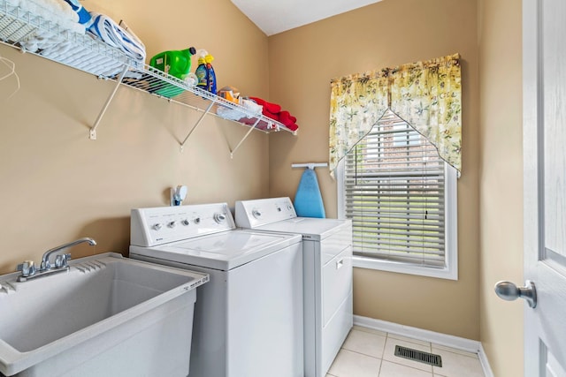 washroom with laundry area, visible vents, a sink, baseboards, and separate washer and dryer