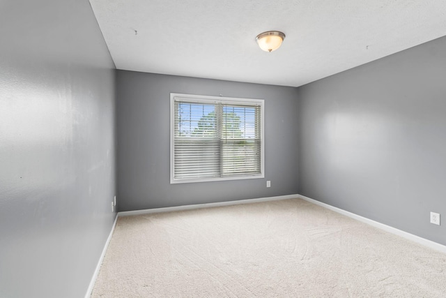 spare room with baseboards and carpet