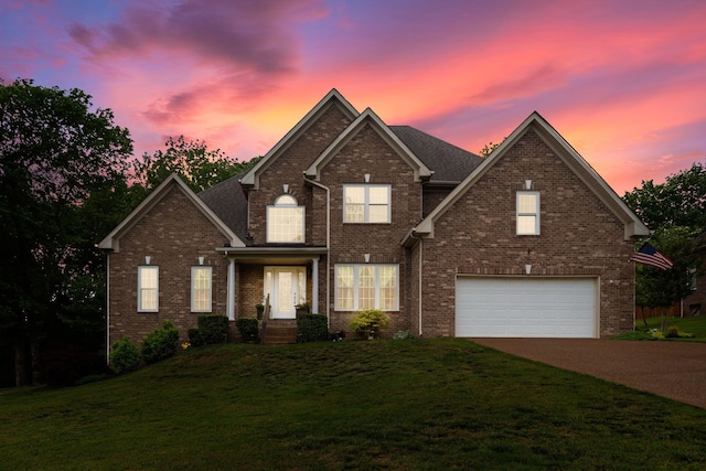 traditional-style house with a lawn, brick siding, an attached garage, and driveway