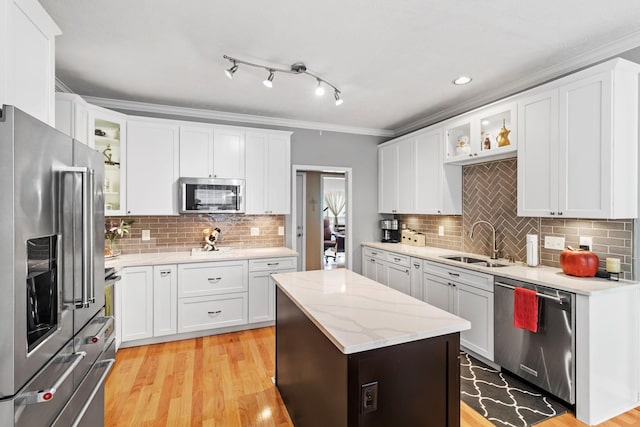 kitchen featuring appliances with stainless steel finishes, a sink, a center island, white cabinetry, and tasteful backsplash