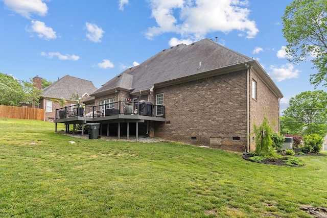 back of property featuring crawl space, fence, a wooden deck, a yard, and brick siding