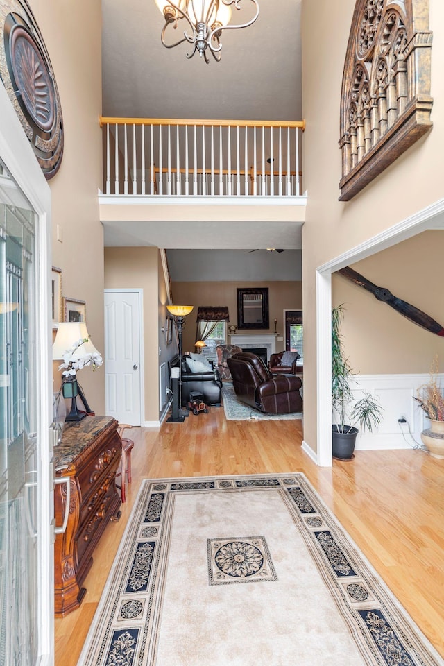 entrance foyer featuring wood finished floors, a high ceiling, a notable chandelier, and a fireplace