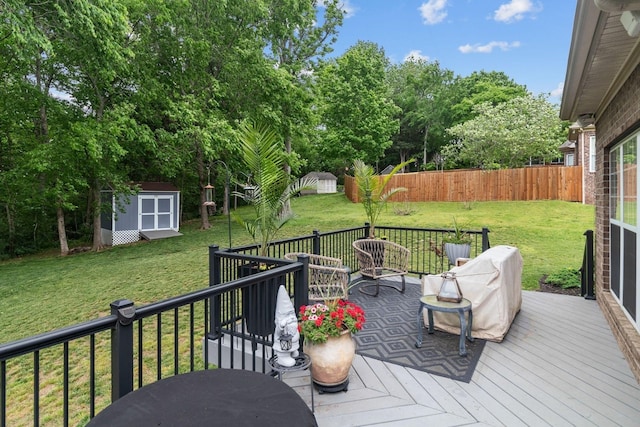 wooden terrace featuring fence, a storage shed, a yard, and an outdoor structure