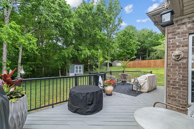 deck featuring fence, area for grilling, a shed, an outbuilding, and a yard