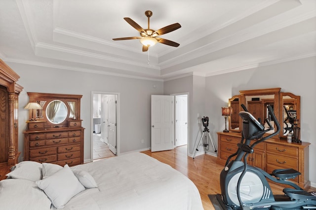 bedroom featuring a tray ceiling, crown molding, and light wood-type flooring