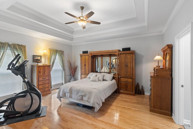 bedroom with baseboards, ornamental molding, ceiling fan, a raised ceiling, and light wood-type flooring
