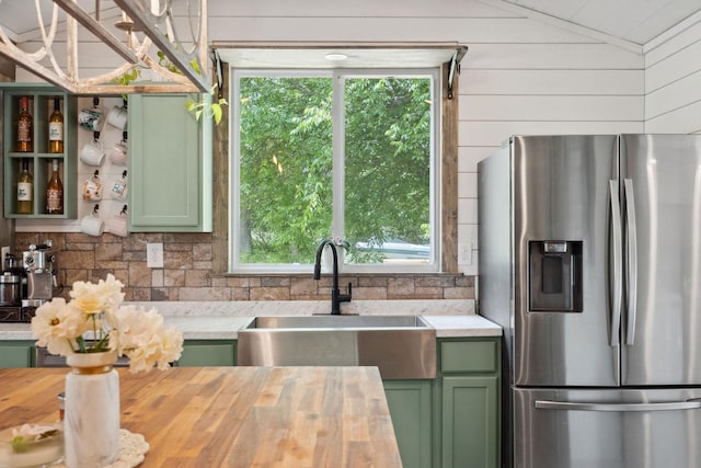 kitchen with a sink, green cabinets, stainless steel refrigerator with ice dispenser, and butcher block countertops