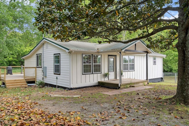 back of property with board and batten siding, fence, a wooden deck, and metal roof