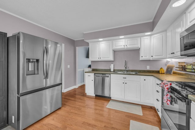 1204 Wood Pines Ln, Hixson, TN 37343 - kitchen featuring appliances with stainless steel finishes, a sink, ornamental molding, light wood-type flooring, and white cabinetry