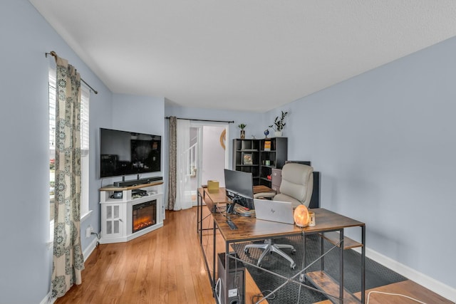 1204 Wood Pines Ln, Hixson, TN 37343 - home office with a glass covered fireplace, light wood-style floors, and baseboards