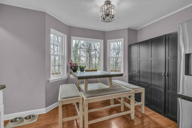 1204 Wood Pines Ln, Hixson, TN 37343 - dining area with a chandelier, light wood-style flooring, a textured ceiling, crown molding, and baseboards