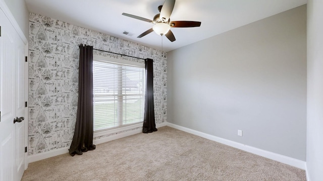 spare room with carpet floors, a ceiling fan, and baseboards