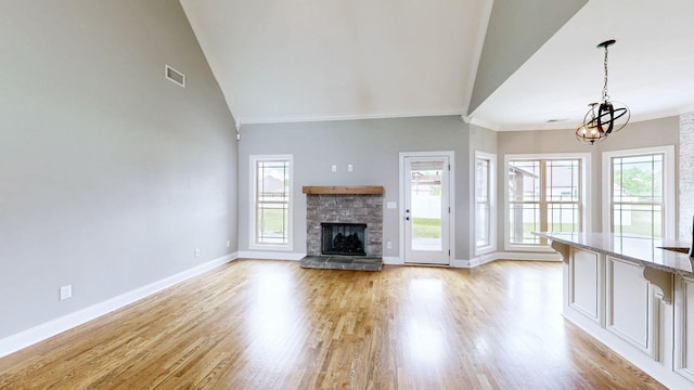 unfurnished living room featuring an inviting chandelier, a wealth of natural light, visible vents, and baseboards