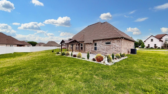 back of property with a patio area, fence, brick siding, a lawn, and central AC unit