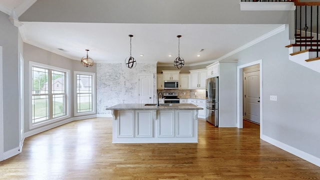 kitchen featuring a sink, wood finished floors, ornamental molding, white cabinetry, and appliances with stainless steel finishes