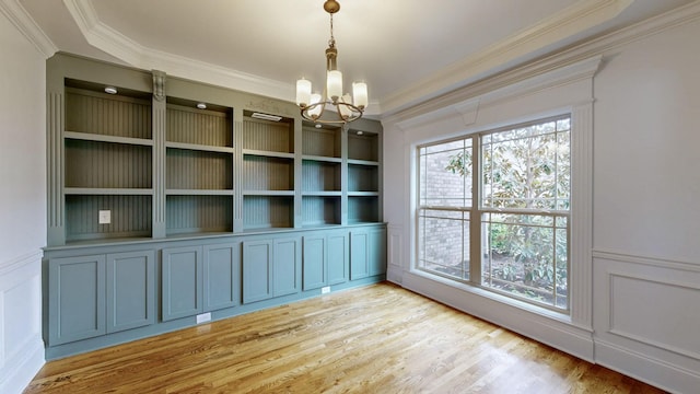 unfurnished dining area featuring crown molding, a notable chandelier, and light wood-type flooring