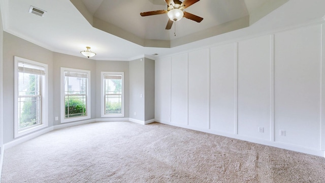 carpeted spare room with a raised ceiling, a wealth of natural light, a ceiling fan, and visible vents