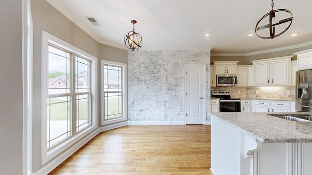 kitchen featuring light wood-style flooring, ornamental molding, visible vents, a chandelier, and appliances with stainless steel finishes