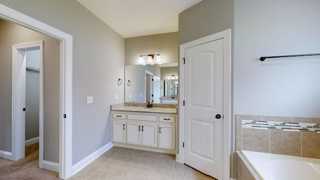 bathroom featuring tile patterned floors, a garden tub, baseboards, and vanity