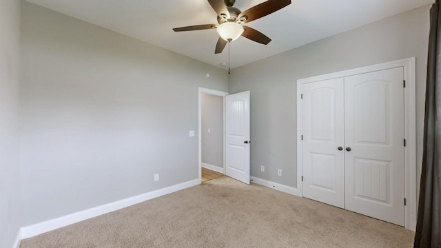 unfurnished bedroom with light colored carpet, a closet, baseboards, and a ceiling fan