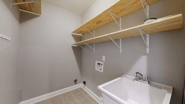 clothes washing area with light tile patterned floors, a sink, washer hookup, laundry area, and baseboards