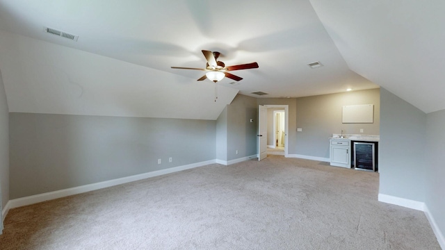 additional living space with beverage cooler, a ceiling fan, visible vents, light carpet, and lofted ceiling