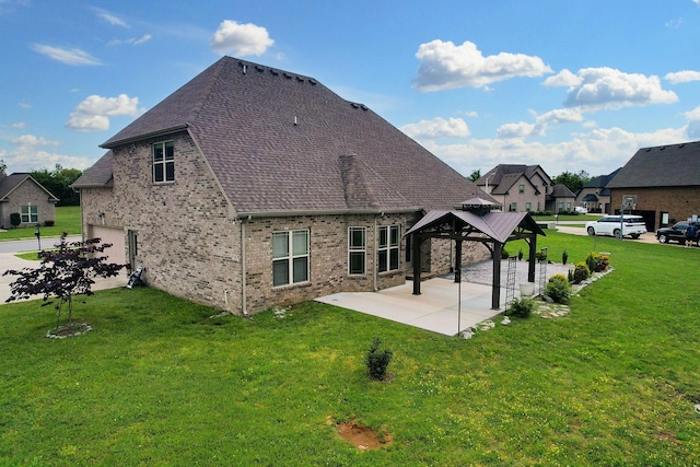 rear view of house with a yard, an attached garage, a patio area, a gazebo, and roof with shingles