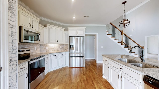 kitchen featuring hanging light fixtures, a sink, stainless steel appliances, light stone countertops, and decorative backsplash