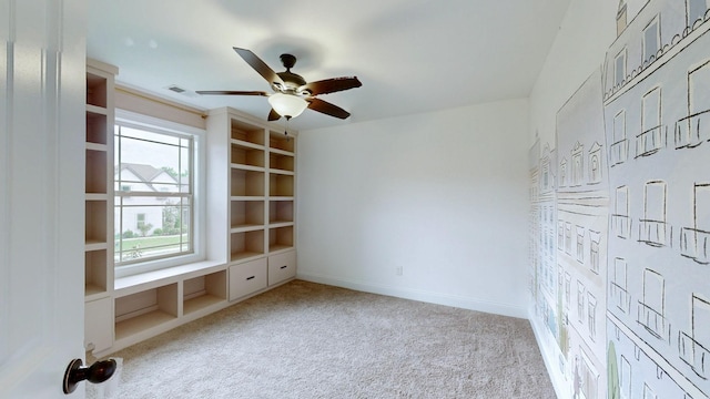 carpeted empty room featuring ceiling fan, baseboards, visible vents, and built in shelves