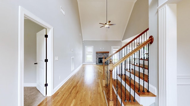 entryway featuring baseboards, ceiling fan, high vaulted ceiling, stairway, and light wood-type flooring