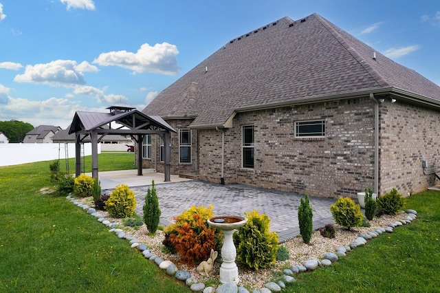 back of property featuring a gazebo, fence, brick siding, a patio, and a lawn