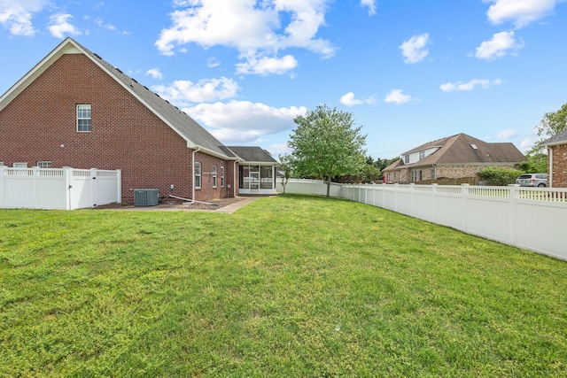 view of yard with a fenced backyard, a patio, a sunroom, and central AC