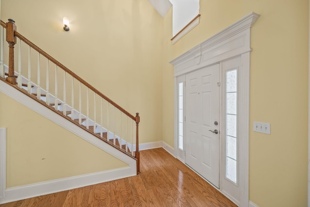 entryway with baseboards, stairs, wood finished floors, and a healthy amount of sunlight